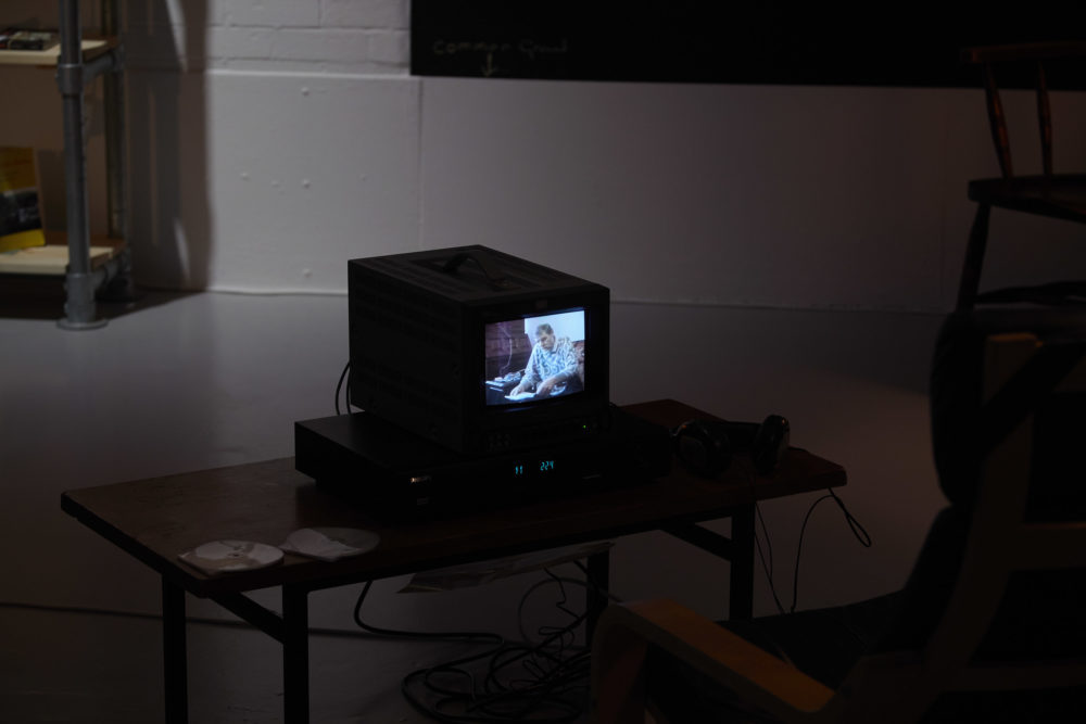 A small television screen in the galleries sits atop a table, a lounger chair can just be seen in the bottom right foreground of the image.