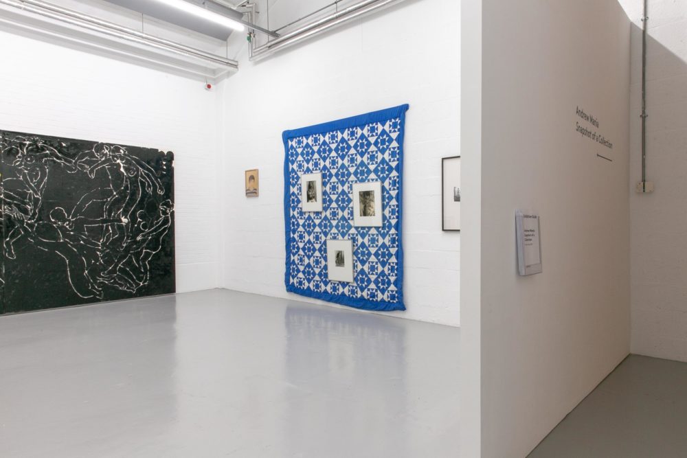 The white corner gallery houses a large black painting of dancers and a large blue and white patchwork quilt.