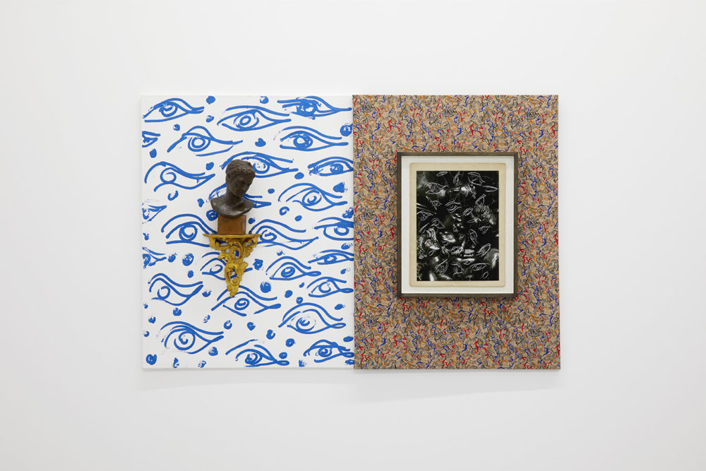 The picture is split in two, on the left blue and white fabric depicting eyes. On top of this is a rococo shelf bracket with a brass bust atop it. On the right is a busily patterned background in purple, red and blue, and a frame in the centre that shows a photograph that has had the eye motif of the neighbouring blue and white fabric into it.