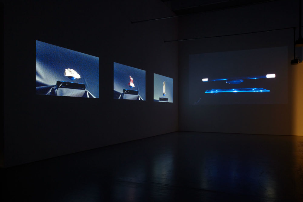 Installation view of Anna Franceschini BEFORE THEY BREAK, BEFORE THEY DIE, THEY FLY! II (2014). Projections of hovering objects show in a dimly lit gallery.