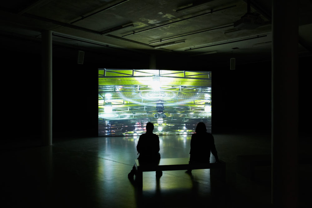 Installation view of Anna Franceschini THE PLAYER MAY NOT CHANGE HIS POSITION (2009). A projection of a fairground shows in a dimly lit gallery.
