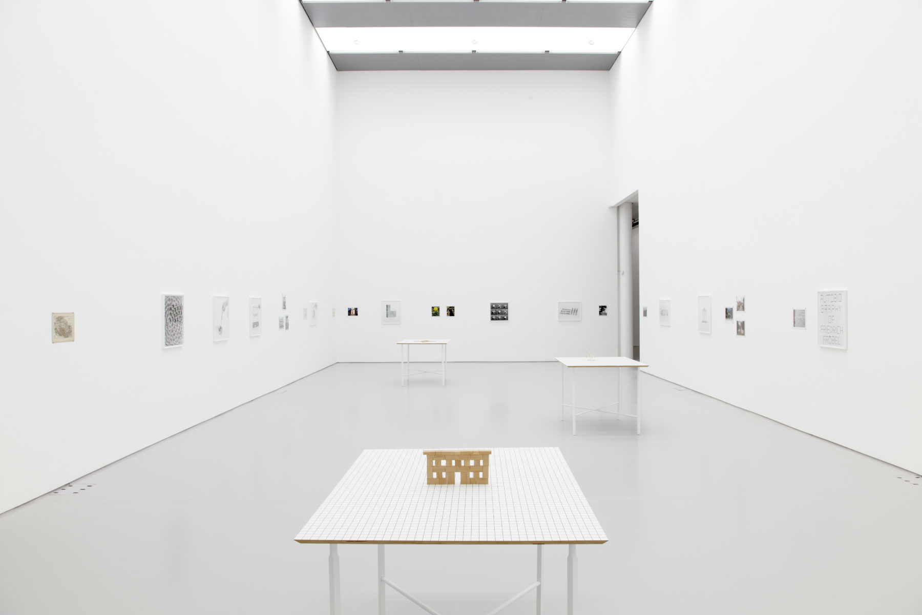 Installation view of Aurélien Froment Fröbel Fröbeled (2014). A white table has a small house on it.