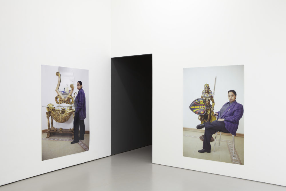 Installation view of Bloomberg New Contemporaries (2013). Photographs of a woman posing next to artefacts.