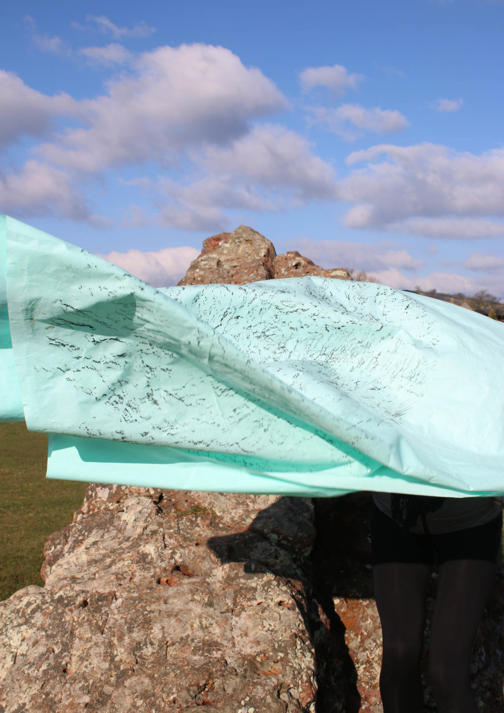 Bryony Gillard's work: a brass rubbing has been taken of a large neolithic stone, the brass rubbing blows in the breeze.