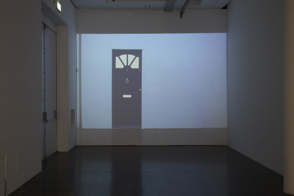 Installation view of Cezary Bodzianowski, Tea Back (2011). A projection of another part of the exhibition is screened onto a wall.