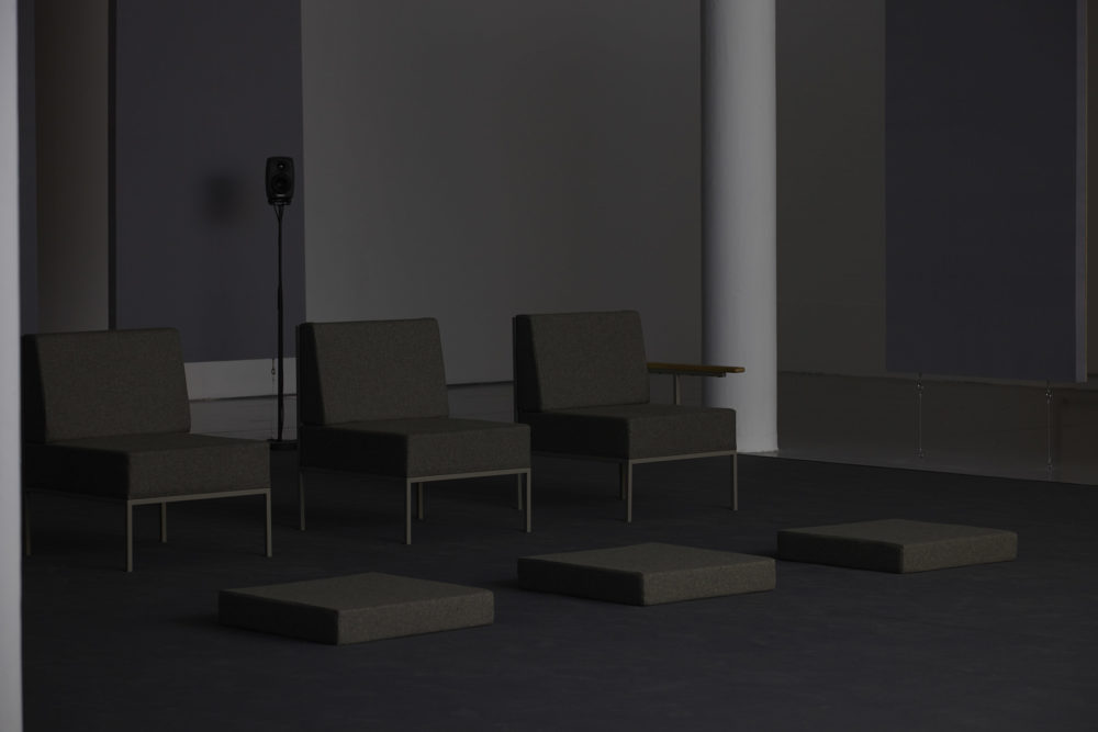 Three large retro chairs, that would not look out of place in a waiting room, sit in a row - three cushions that would fit their seats lie in front of them.