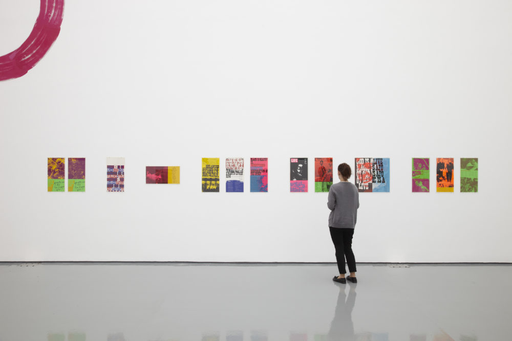 Installation view of Ciara Phillips and Corita Kent, Pull Everything Out (2012) A visitor studies a selection of screenprinted posters.