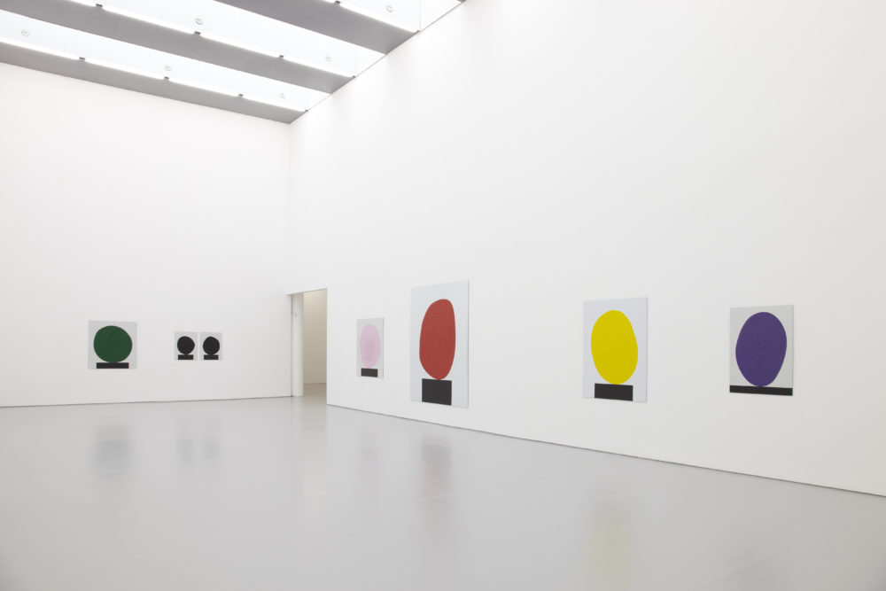 Installation view of David Batchelor Flatlands (2013). Each work is a painting of a blob balancing on a black rectangle.