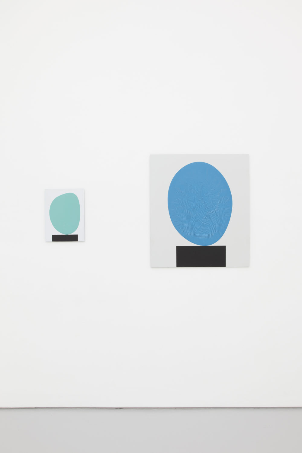 Installation view of David Batchelor Flatlands (2013). Two works side by side. Each work is a painting of a blue blob balancing on a black rectangle.