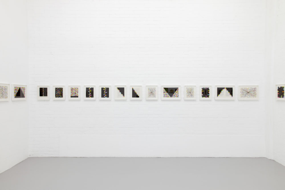 Installation view of David Batchelor Flatlands (2013). Small images are hung in white frames on white walls.