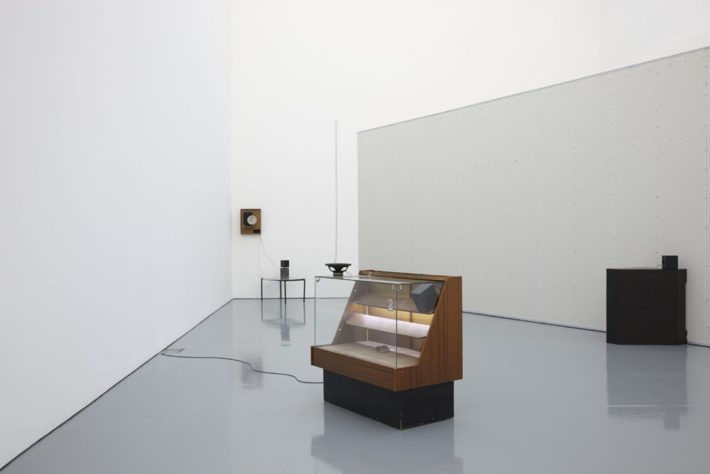 Installation view of Haroon Mirza. A formica covered glass display unit is lit up in the centre of the gallery.