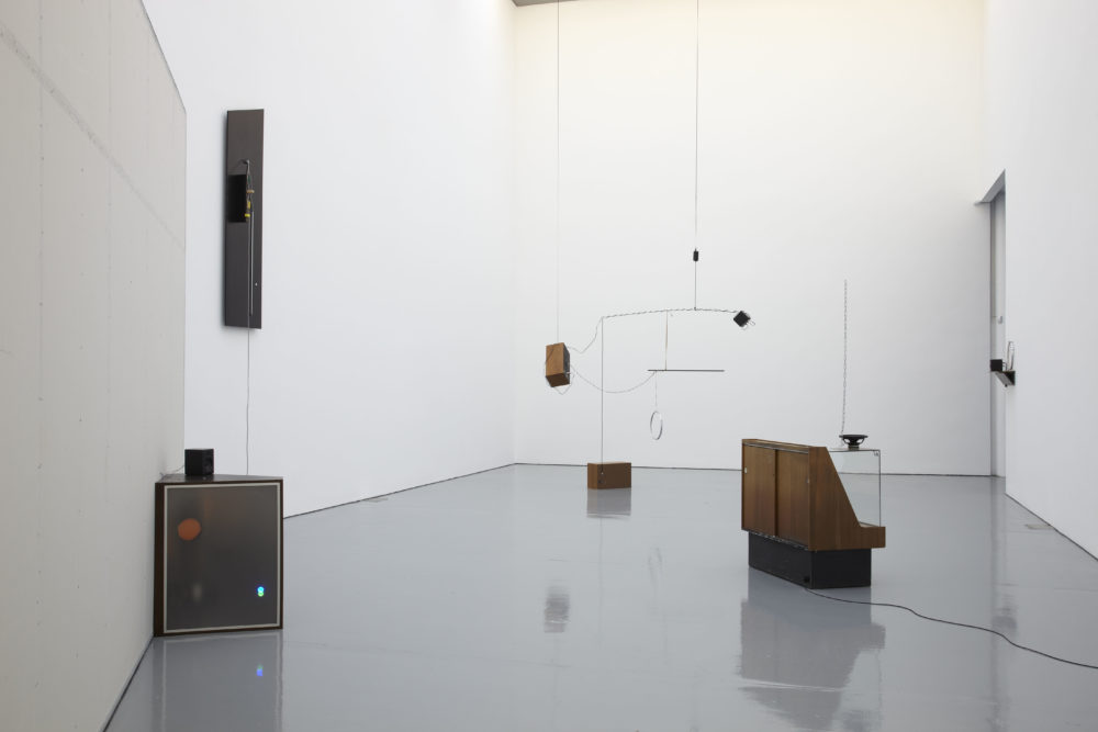 Installation view of Haroon Mirza. Unusual retro electronic instruments sit in the gallery, some suspended from the ceiling.