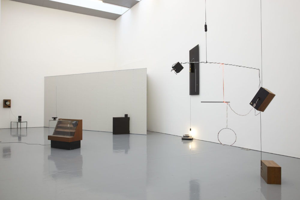 Installation view of Haroon Mirza. Formica speakers are suspended from the ceiling.