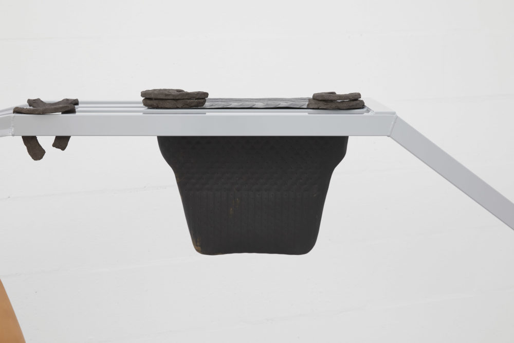 Harriet Bowman, (Car) display unit (2018) Steel, display items (mixed media) (detail); Horseshoes (2018) Vulcan black stoneware clay (fired); Accessories: glossed car mats. Installation view, All Round-er (sad sale), Spike Island (2018) Photograph by Stuart Whipps