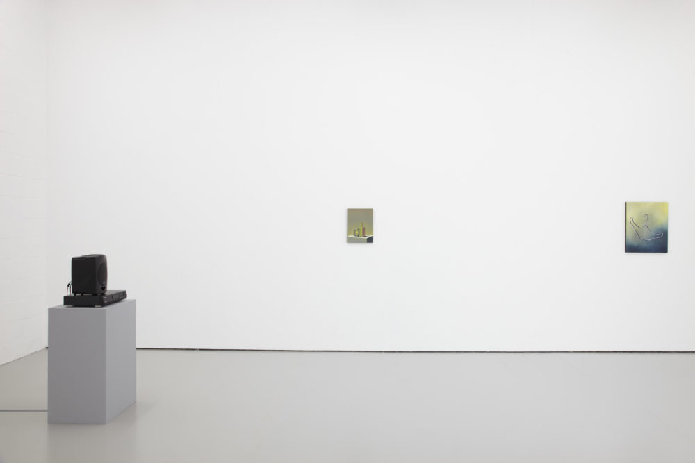 Installation shot: Two unframed paintings hang on white walls, a plinth holds a stereo and a speaker.