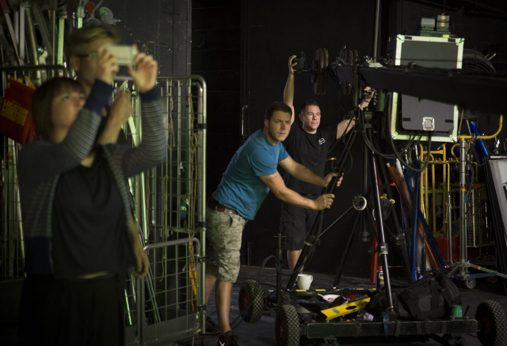 Production shot: Four crew members work on a film set.