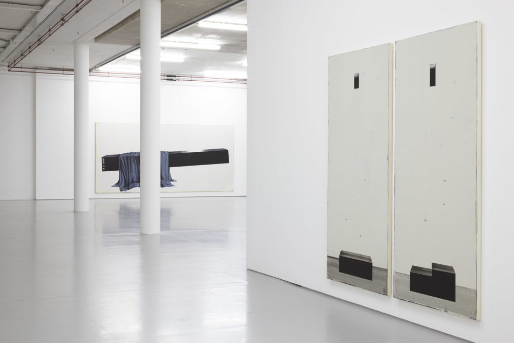 Three large black and white paintings hang in the gallery.