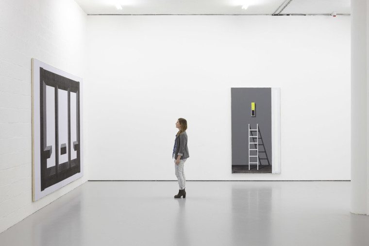 A visitor studies the paintings on the gallery wall.