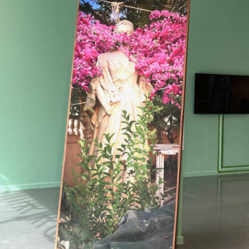 Mirror installation reflecting sculpture and bright pink flowers
