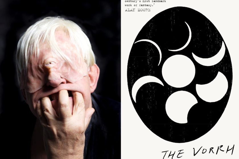 The author Brian Catling, dressed as a cyclops, next to their book The Vorrh.