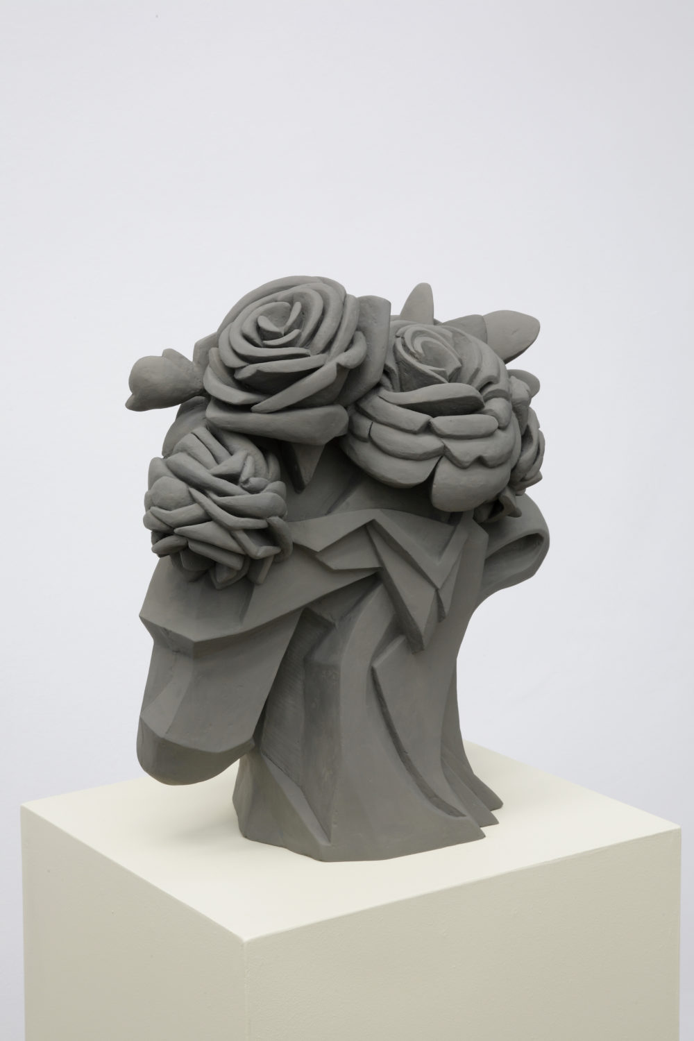 Installation view of Prophet (2008). A geometric sculpture, reminiscent of roses, made of clay sits on a plinth.