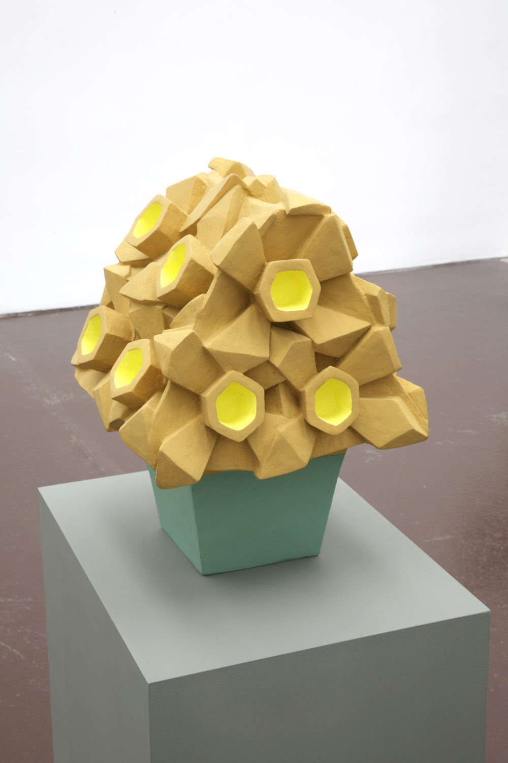 Installation view of Prophet (2008). A yellow geometric sculpture made of clay is designed to look like a bouquet of flowers.