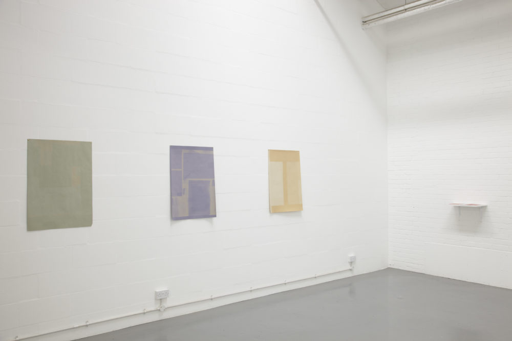 Installation view of Sara MacKillop, Faded Paper (2011). Three sheets of sugar paper, faded by the sun, are pinned to the white gallery wall.