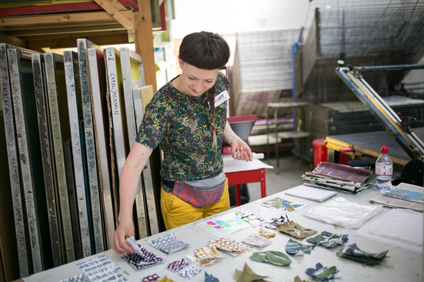 A member of Spike Print Studio lays out small bits of paper that have been printed with highly decorative designs.