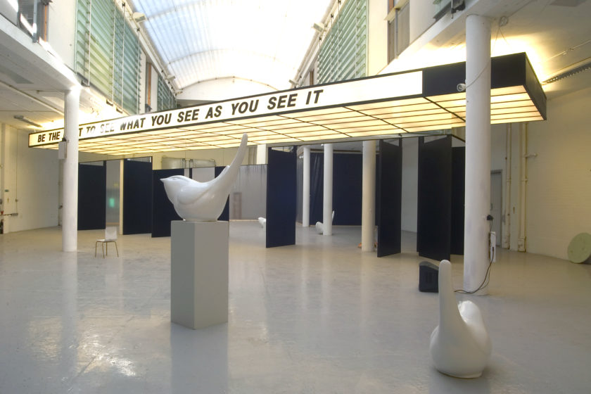 Installation view of Spin Cycle (2004). A canopy that looks like a cinema entrance hangs from the gallery ceiling, 