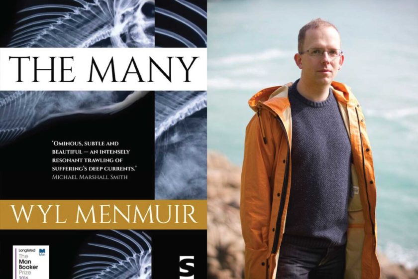 A photograph of the author Wyl Menmuir next to their book The Many.