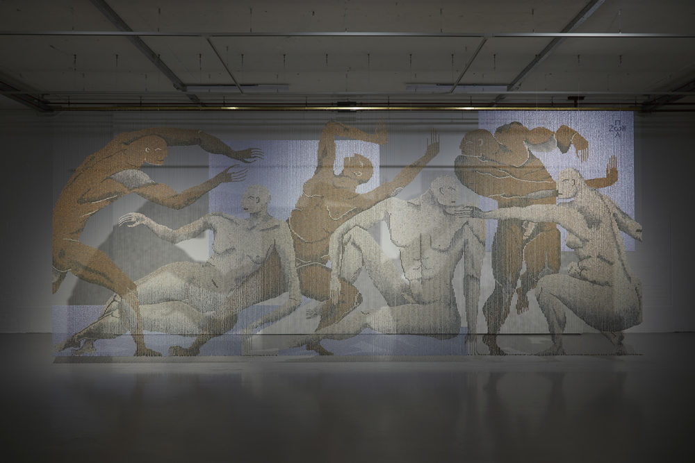 A large bead curtain stretching from the ceiling to the ground - the beads are depicting a series of nudes (six) interacting with one another, they look hostile.