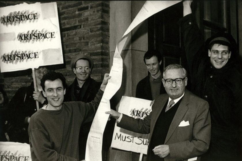 Black and white photograph of people holding a long paper petition