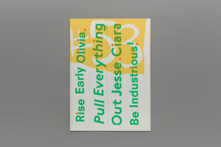 A closed book. On the cover are the words “Rise Early Olivia. Pull everything out Jesse. Ciara be industrious!” screenprinted in green over a yellow and white graphic background.