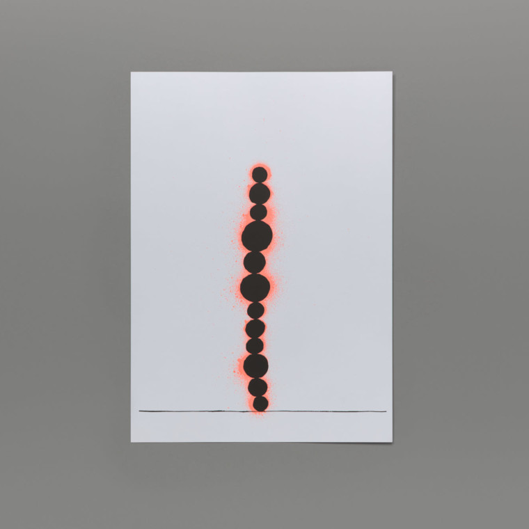 Upon a thin black line that crosses the width of the page 12 black circles of different sizes are stacked on top of each other with neon orange spray painted circles behind them. The edition is photographed on a grey background.