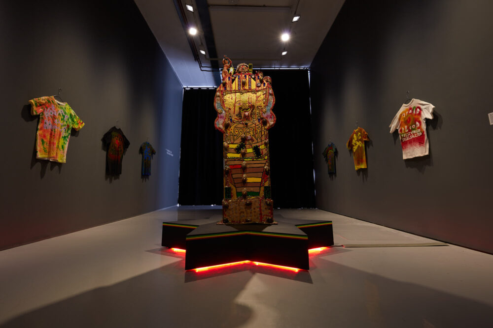 Gallery view of a makeshift alter, atop a black star, lit from below by a red light.