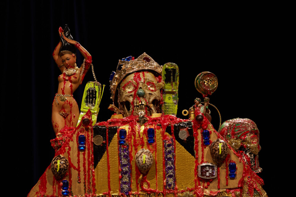 Gallery view of a close up of the top of an alter, encrusted with skulls, dolls, shells and glitter.