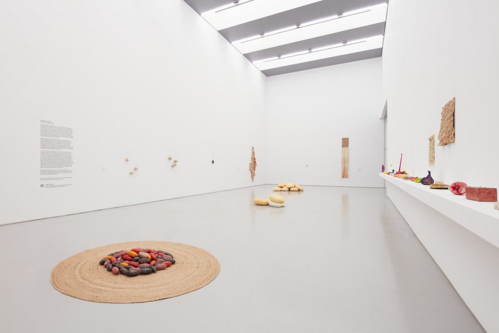 A wide angle view of Veronica Ryan's exhibition Along a Spectrum at Spike Island, a gallery space filled with light and colourful sculptures and objects positioned on the gallery floor and walls