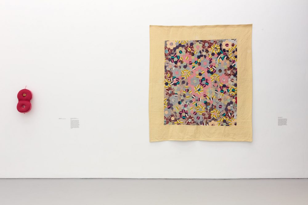 A photograph of two works by Veronica Ryan installed on a white gallery wall, including: Untitled (2019) Medical cushion, orange peel, thread and Safe Spaces (1988-2019) Fabric, ink, thread