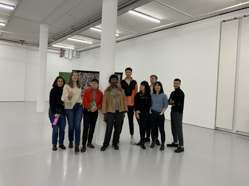 Eight participants stand in our gallery with a member of our curatorial team.