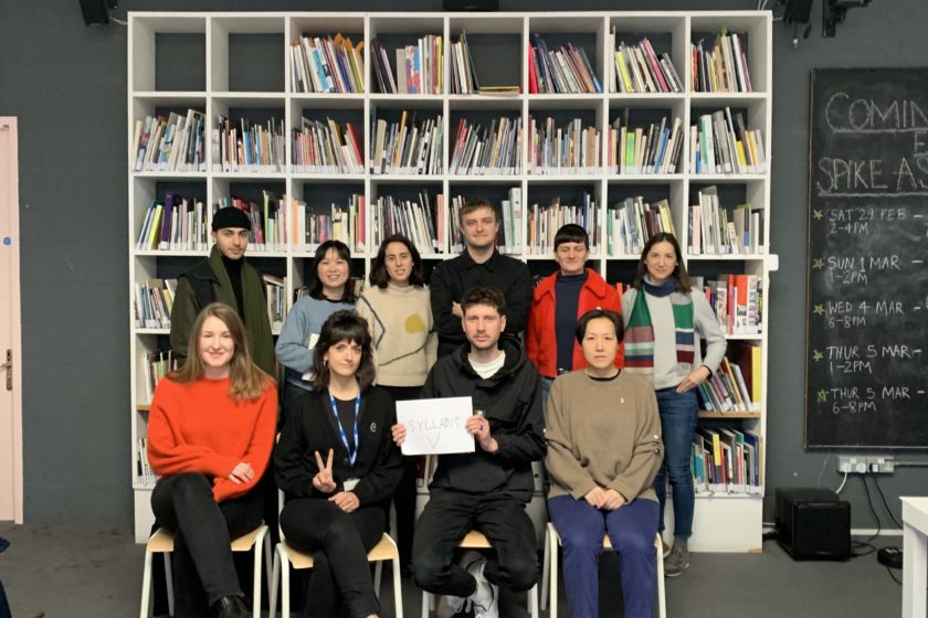 Ten people gather in front of a bookcase looking at the camera.