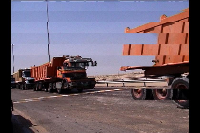 Large red trucks drive across the shot. The image has been manipulated so that strips of the image are offset from one another.