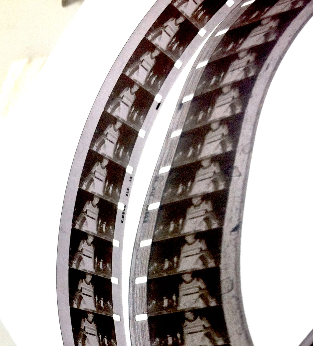 Vicky Smith's work 'jinty', A photograph of two strips of 16mm black and white film reel, curving over a white background