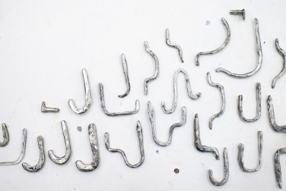 On a white painted brick wall, a range of cast pewter objects