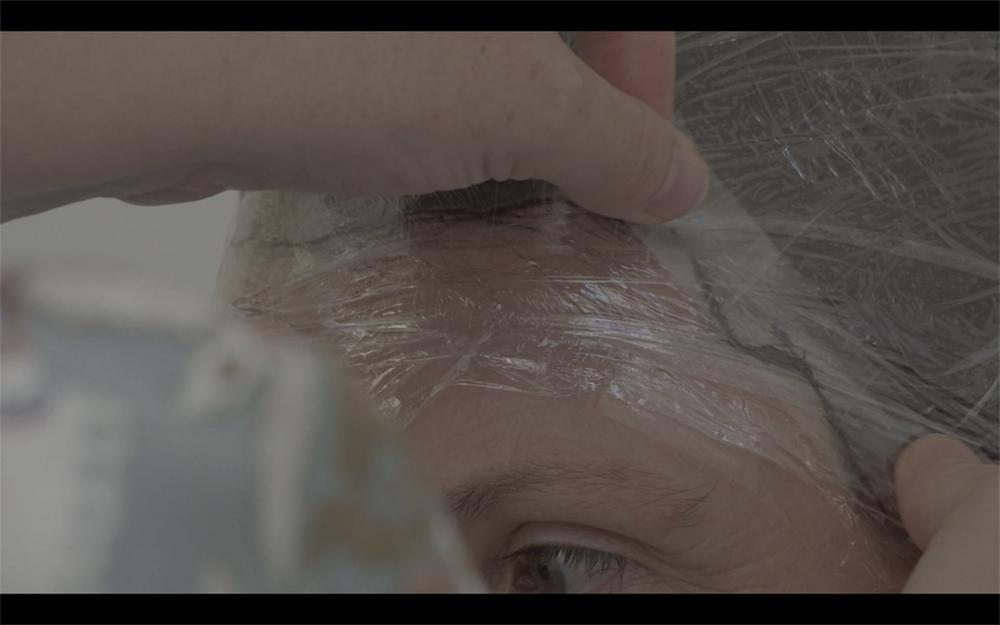 Woman wrapping cling film around forehead