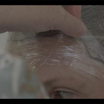 Woman wrapping cling film around forehead