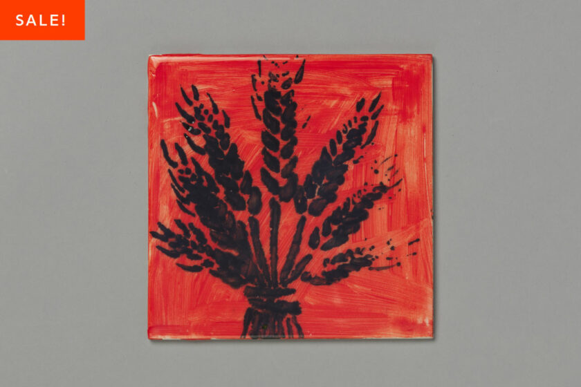 A painted tile edition by Lucy Stein of a wheat sheaf in black against a red background