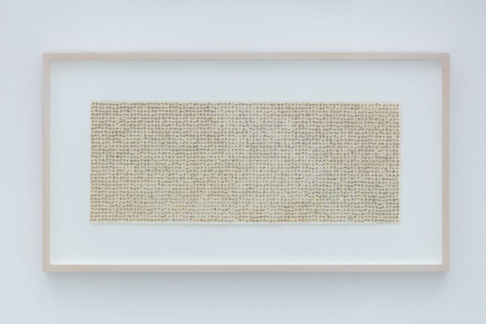 A photograph of ink on paper collage by Howardena Pindell's hanging in a gallery