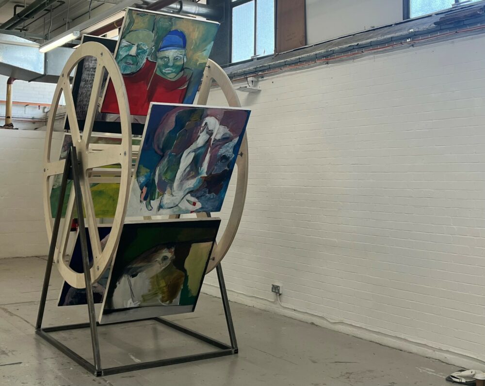 This images shows a number of painted canvases by Rosie Bayliss that are placed on a wheel within a studio.