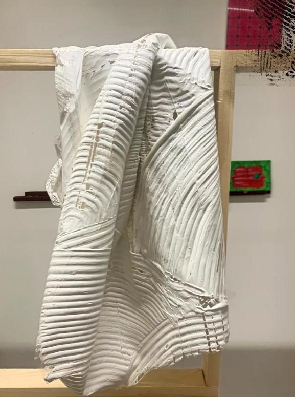 A close-up of a piece of fabric with plaster designs hanging from a wooden frame