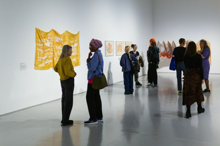 People standing and chatting in a gallery filled with sculptures